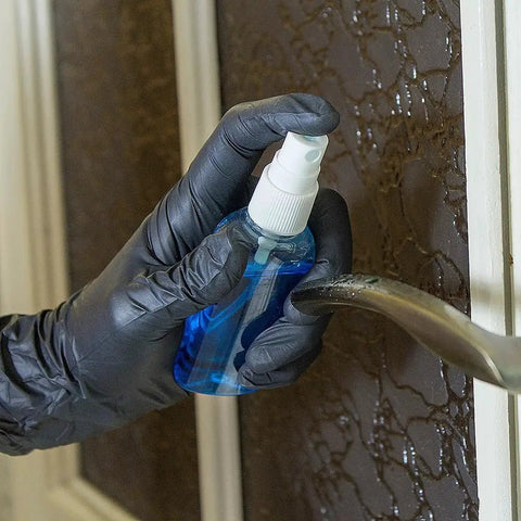 Hand wearing Black Nitrile Gloves 4 Mil Large 100 Count Chemical Resistant Food Safe, using spray bottle on door handle
