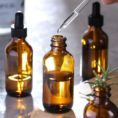 Close-up of 4 Pack 30ml Dark Amber Glass Dropper Bottles With 1 Funnel And 4 Labels, showing a dropper in use with amber bottles.