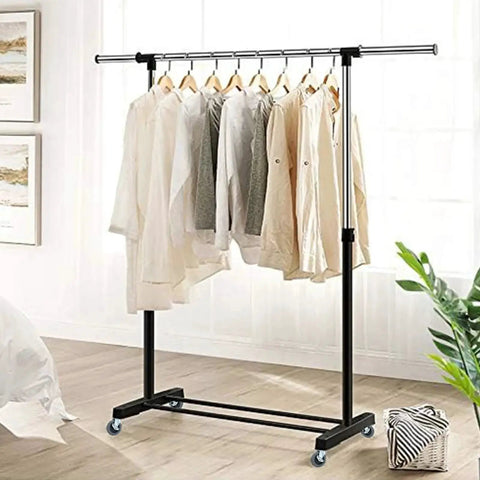 Clothing rack with shirts and jackets hanging in a bright room, showcasing metal frame and caster wheels on hardwood floor.
