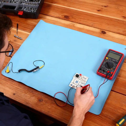 Person using Anti Static ESD Mat For Electronics Repair And PC Building with grounding wire and multimeter on desk