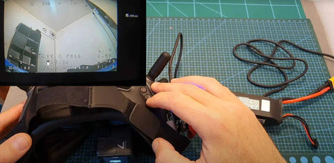 5.8G Analog Receiver Module Adapter Board connected to FPV goggles, showing digital screen view for enhanced video reception in aerial racing.