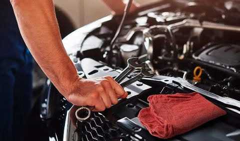 Mechanic using tools with Red Cotton Shop Towels Pack Of 150 14 By 14 Inch Absorbent Cleaning Rags on car hood for garage use.