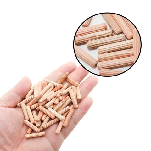Hand holding 48 Pack 5Mm By 25Mm Wooden Dowel Pins With Fluted Beveled Ends For Shelves And Woodworking Hardwood Dowels For A Tight Friction Fit 0.2 Inch By 1 Inch Durable Wooden Pegs For Quick DIY Furniture Assembly, shown with a close-up inset of dowels on a surface.