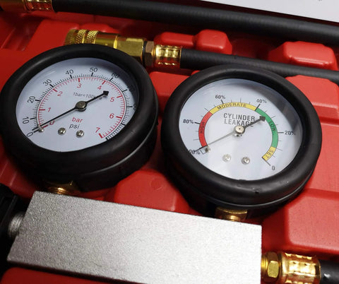 Dual-gauge cylinder leak-down tester with brass fittings in a red tool case for engine compression diagnostics.
