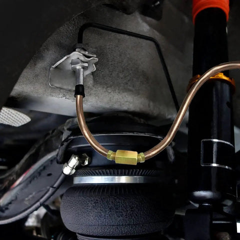 Copper-nickel 3/16 inch brake line with brass fittings installed under a vehicle near suspension.