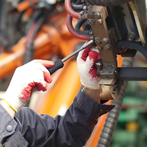 Person using screwdriver on machinery part in industrial setting