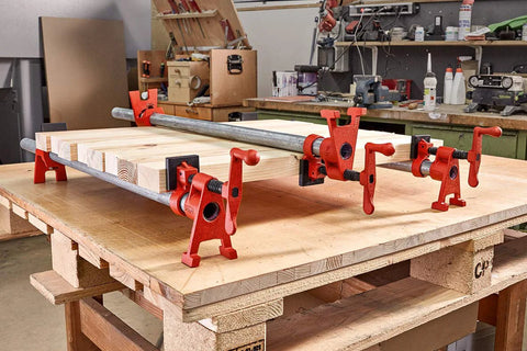 Bessey BPC-H34 3/4-in H-style pipe clamps, red steel, securing a wooden board on a workbench
