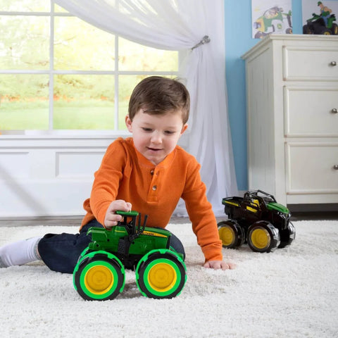 Child playing with John Deere Monster Treads Lightning Wheels Monster Truck Toy With Motion Activated Lights indoors on carpet