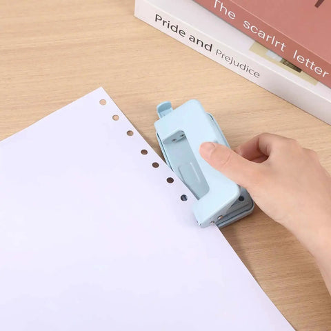 Using Two-Hole Paper Puncher With Adjustable Guide and Labor-Saving Handle on white paper, showcasing 0.23 inch holes, blue