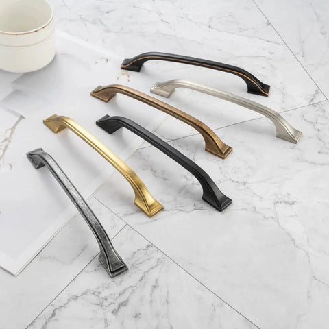 Five Pack 3 Inch Oil Rubbed Bronze Cabinet Pulls alongside different colored metal pulls on a marble surface.