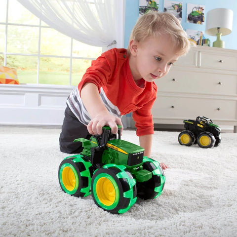 Child playing with John Deere Monster Treads Lightning Wheels Monster Truck Toy With Motion Activated Lights on carpet