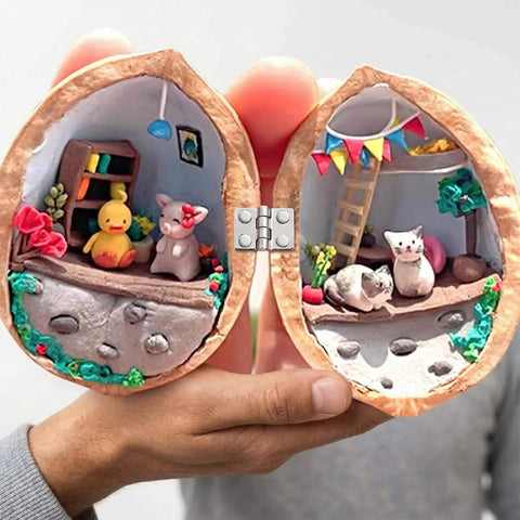 Miniature diorama inside a walnut shell showing a crafted scene with small figurines and furniture, hinged at the center.