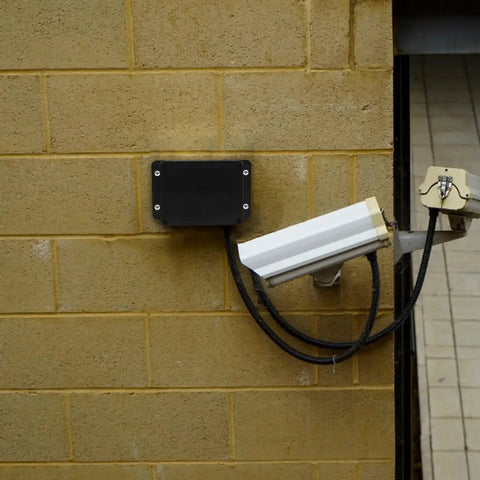 Beefy Black Plastic Waterproof Electrical Junction Box 115x90x55mm With Mounting Ears installed outdoors on yellow brick wall