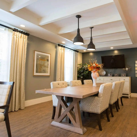 Modern dining room with wooden table, upholstered chairs, pendant lights, and large window curtains.