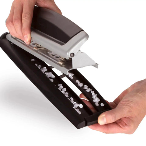 Hands holding Office Workhorse 3 Hole Paper Punch with adjustable settings, emptying punched paper confetti