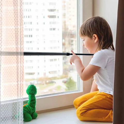 Child near a window secured with a Four Pack Sliding Door Security Bar With Rubber Tips Extendable Tension Rod Adjustable 15.7-27.6 in Black