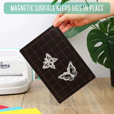 Hand holding Must Have Die Cutting Magnetic Shim Mat Set 6x9 Inch With Card Size Grids And Two Acrylic Cutting Plates For Die Cutting Machines Embossing And Crafting Accessories with metal dies on a grid.