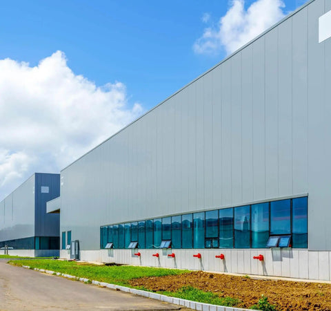 Large industrial warehouse exterior with blue sky background.