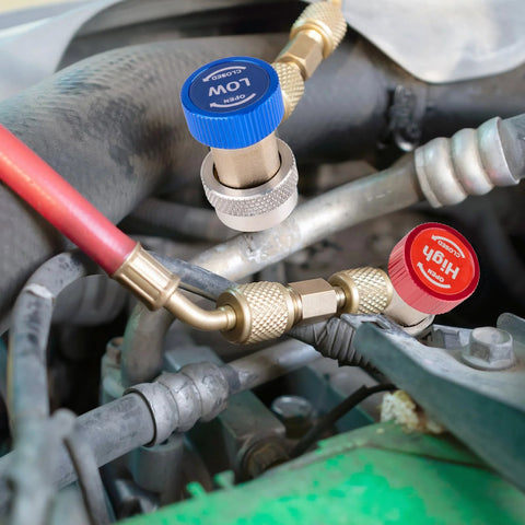 Two automotive A/C refrigerant adapters with blue low-pressure cap and red high-pressure cap, brass fittings on hoses.