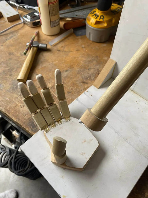 Wooden model hand with articulated fingers on a workbench