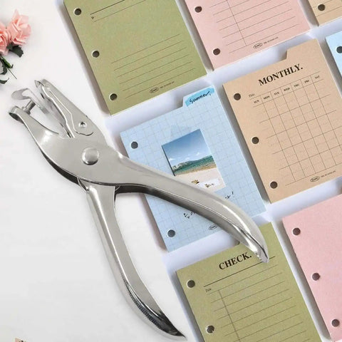 One Eighth Inch Hole Puncher 3mm Metal Paper Punch next to colorful craft sheets, stainless steel, rust resistant tool for DIY projects