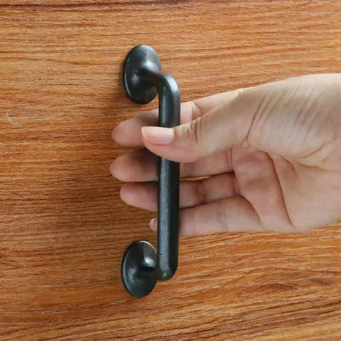 Hand holding Rustic Black Silver Cabinet Handles Set Of 10 Drawer Pulls Zinc Alloy One Piece Die Cast Construction on wooden drawer