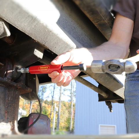 Grease Buster by LockNLube, red tool being used to flush grease from an automotive fitting under a vehicle.