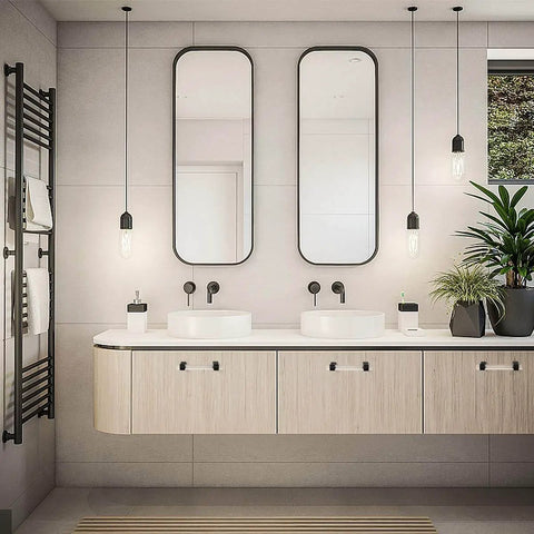 Modern bathroom with sleek vanity, double sinks, black fixtures, hanging mirrors, and pendant lights, with plants for decoration.