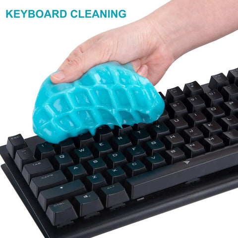 Hand holding reusable blue Cleaning Gel For Car Detailing Putty And Vent Cleaner Goo For Auto Interior Dust Removal Mud Slime on keyboard.
