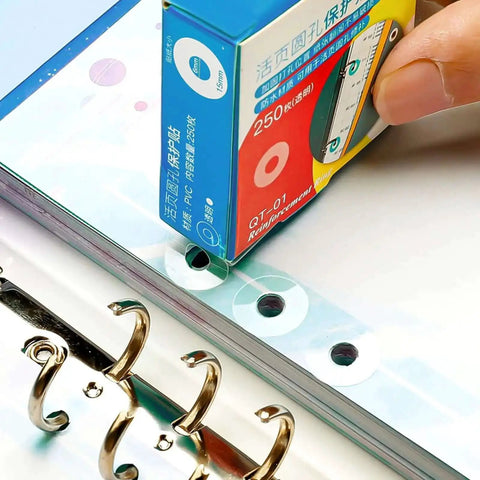 Applying Clear Hole Reinforcement Stickers Pack 1000 Count 4 Boxes Of 250 Easy Peel Self Adhesive on binder pages.