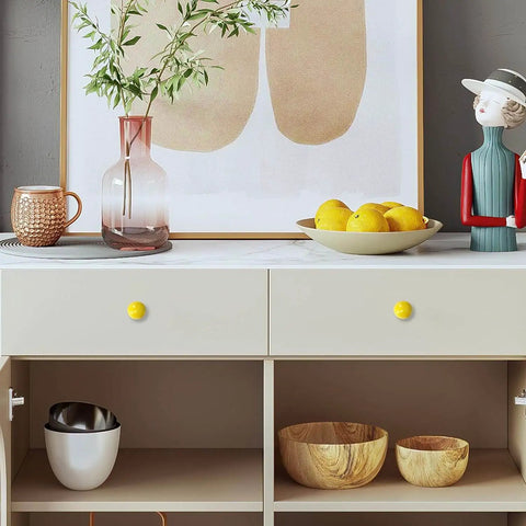 Cabinet with yellow knobs, art, and decorative items displayed in a modern room setting.