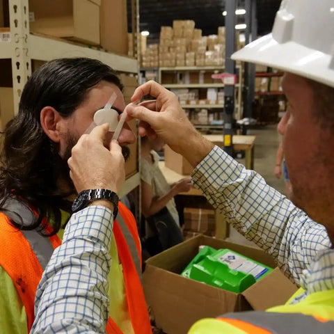 Person applying 4 Piece Eye Wash Kit With Oval Eye Pads, Tape And Emergency Eye Rinse For Fast Eye Relief Grab And Go At Home in a warehouse