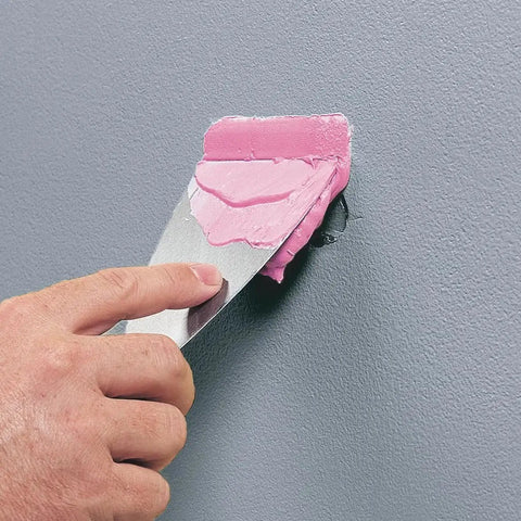 Applying DryDex Dry Time Indicator Spackling for interior and exterior surfaces, pink on application dries white, using a putty knife for wall repair