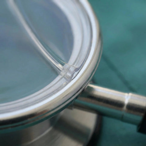 Stethoscope diaphragm chest piece close-up, chrome metal rim and clear membrane, medical auscultation accessory.
