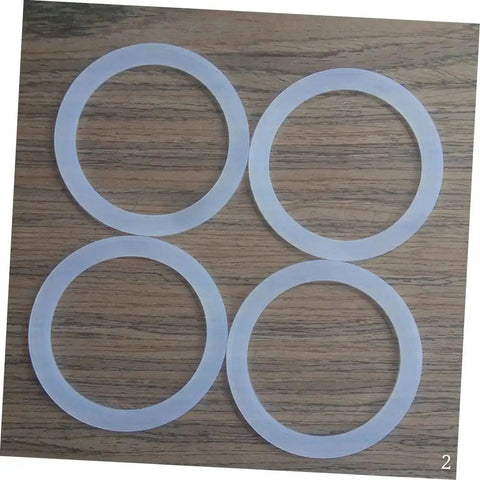 Four white silicone gaskets from Silicone Gasket Replacement Set 10 Pieces For Coffee Pot Lids And Jar Seals on wooden surface.