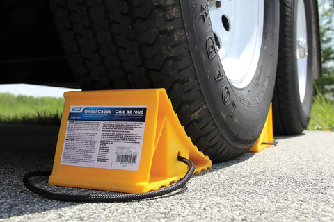 Heavy Duty RV Wheel Chock With Rope Handle For Trailers Up To 26 Inches securing a tire on a trailer