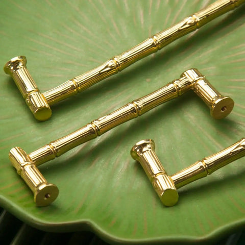 Gold Brass Bamboo Shape Cabinet Handles Set, Antique Brushed Copper Finish, displayed on a green surface