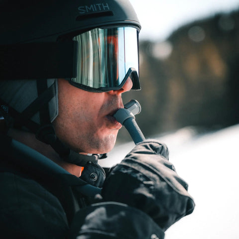 HydraPak insulated drink tube with bite valve; outdoor use, side view of skier wearing helmet and goggles.