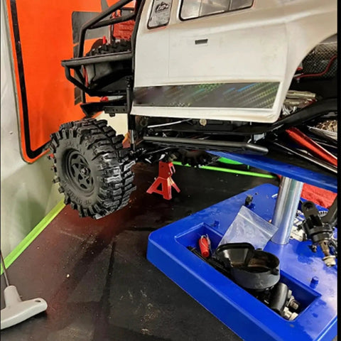 1/10 RC car lifted on blue platform using 4Pcs Adjustable Metal Jack Stands for 1/10 RC Crawler Cars Climbing Jack Set.