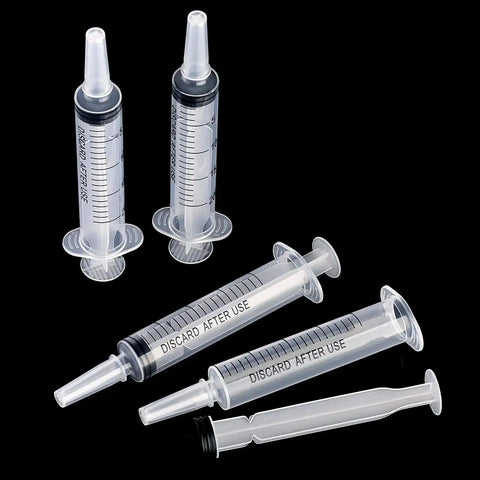 Large Plastic Syringe 4 Pack For Measuring And Dispensing Fluids Sterile Wrapped 20 Ml Syringe Set lying on black background