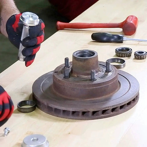 Mechanic using Bearing Race And Seal Driver Set With Nine Sizes Range From 1.565 To 3.180 Inches for wheel installation.