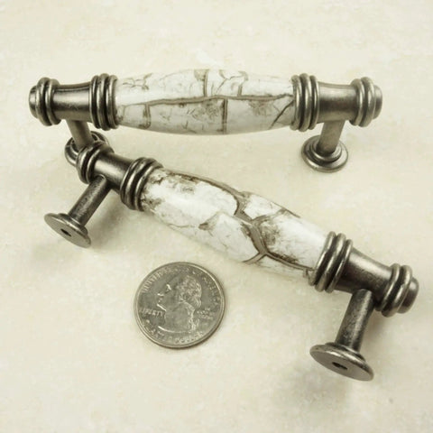 Antique silver white marble cabinet pulls with quarter for scale, detailed design.