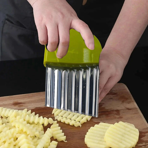 Person using Crinkle Cutter Knife Stainless Steel Wavy Chopper For Potatoes Vegetables Carrots Kitchen French Fry Slicer Tool Green Ergonomic Handle Food Grade on a wooden board.