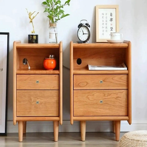 Wooden side tables with drawers and open shelves, decorated with a clock and books on top, in a cozy room setting.
