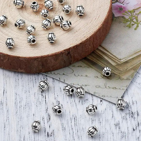 Antique Silver Tibetan Style Pumpkin Spacer Beads 4mm, 100 Piece Set for DIY Jewelry Making on wood and paper background