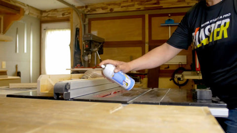 Person applying 6-16-TDL Advanced Dry Lube With Teflon 9.3 Oz Pack Of 6 to a table saw in a woodworking shop