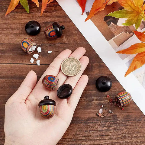 Five Pack Rainbow Wood Acorn Pendant Set With Openable Mini Cremation Urns for Ashes, shown with hand for size comparison, 30x22mm.