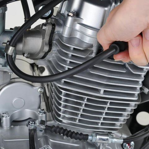 Silicone vacuum hose being installed on a motorcycle engine; black high-temp tubing near the cylinder head
