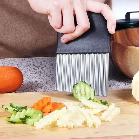 Crinkle Cutter Stainless Steel Wavy Slicer With Black Handle in use cutting cucumber, potato, and carrot on wooden board.