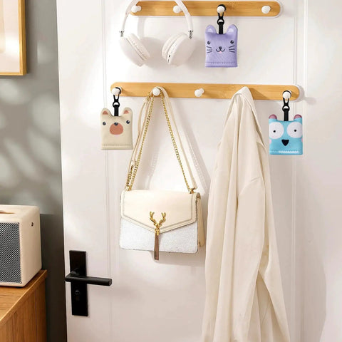 Colorful neoprene pouches hanging on a wooden rack with a white bag and headphones, showcasing versatile storage options.